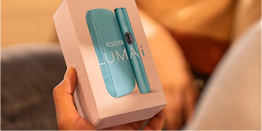 Hands holding an IQOS ILUMA i box.